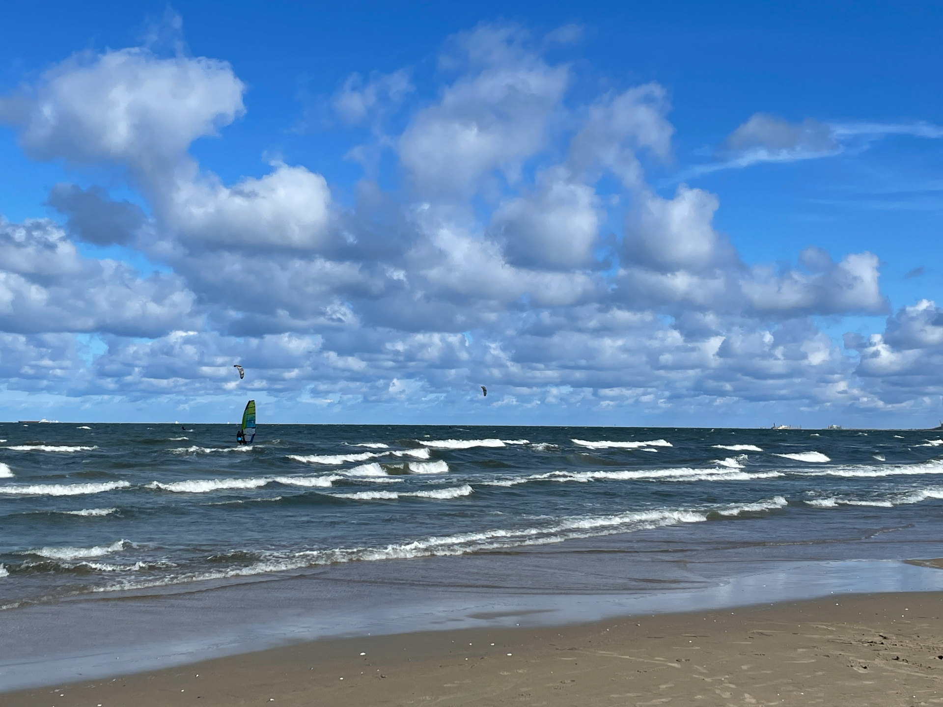 Windsurfer na falach przy plaży pod dynamicznym niebem