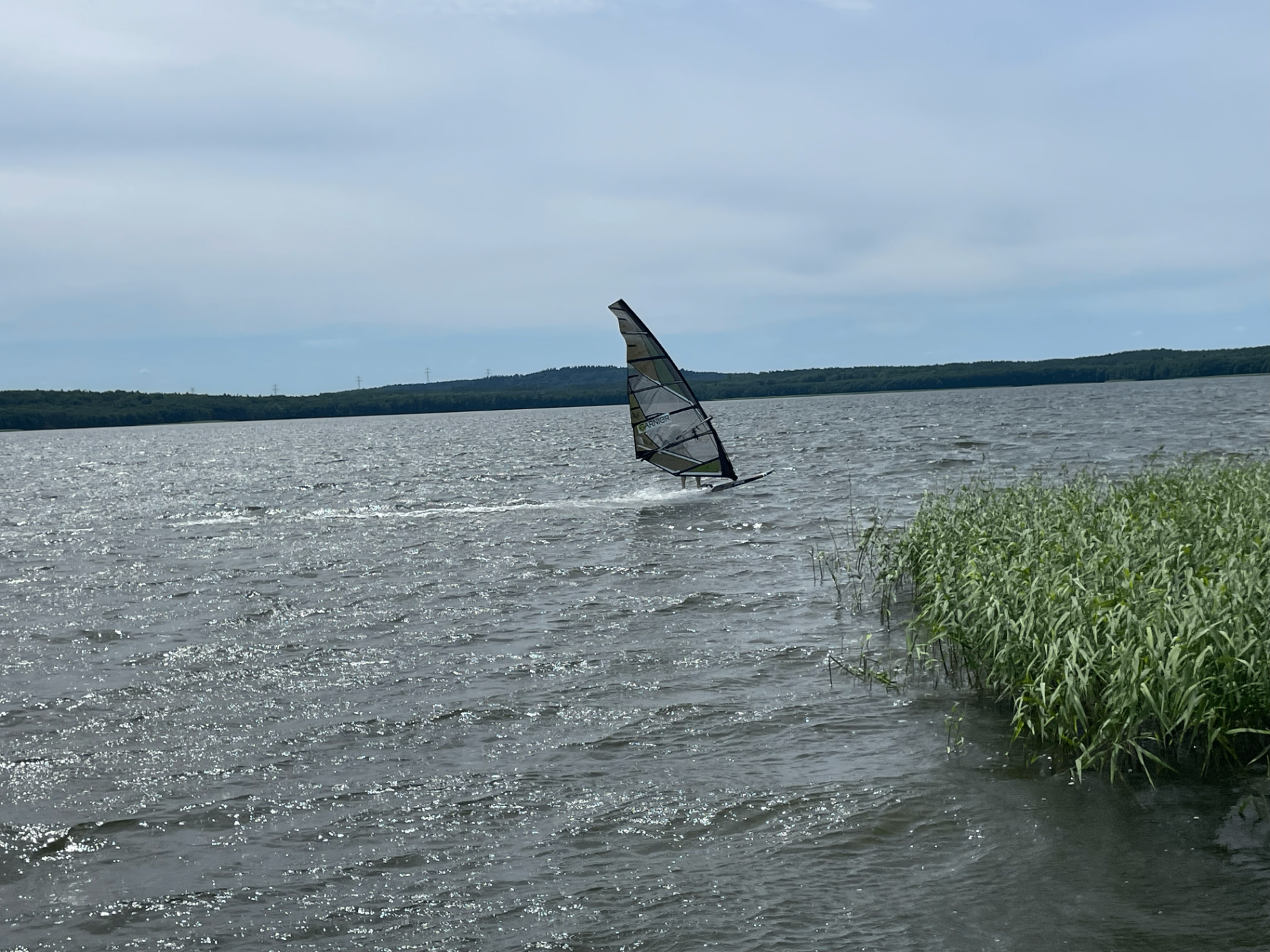 Zawodnik windsurfingu płynący po jeziorze przy brzegu
